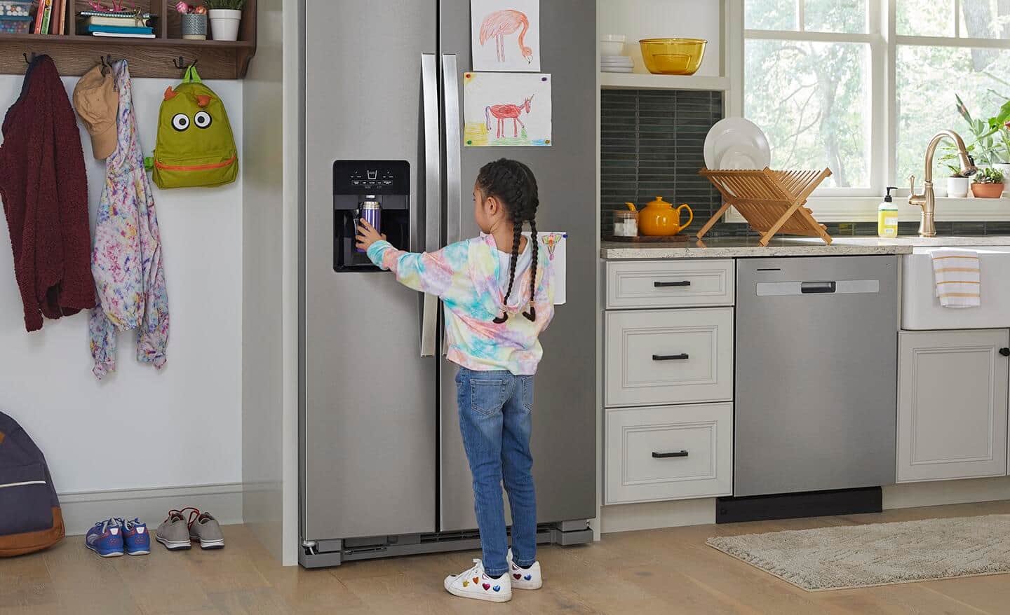 Child getting water from refrigerator dispenser.