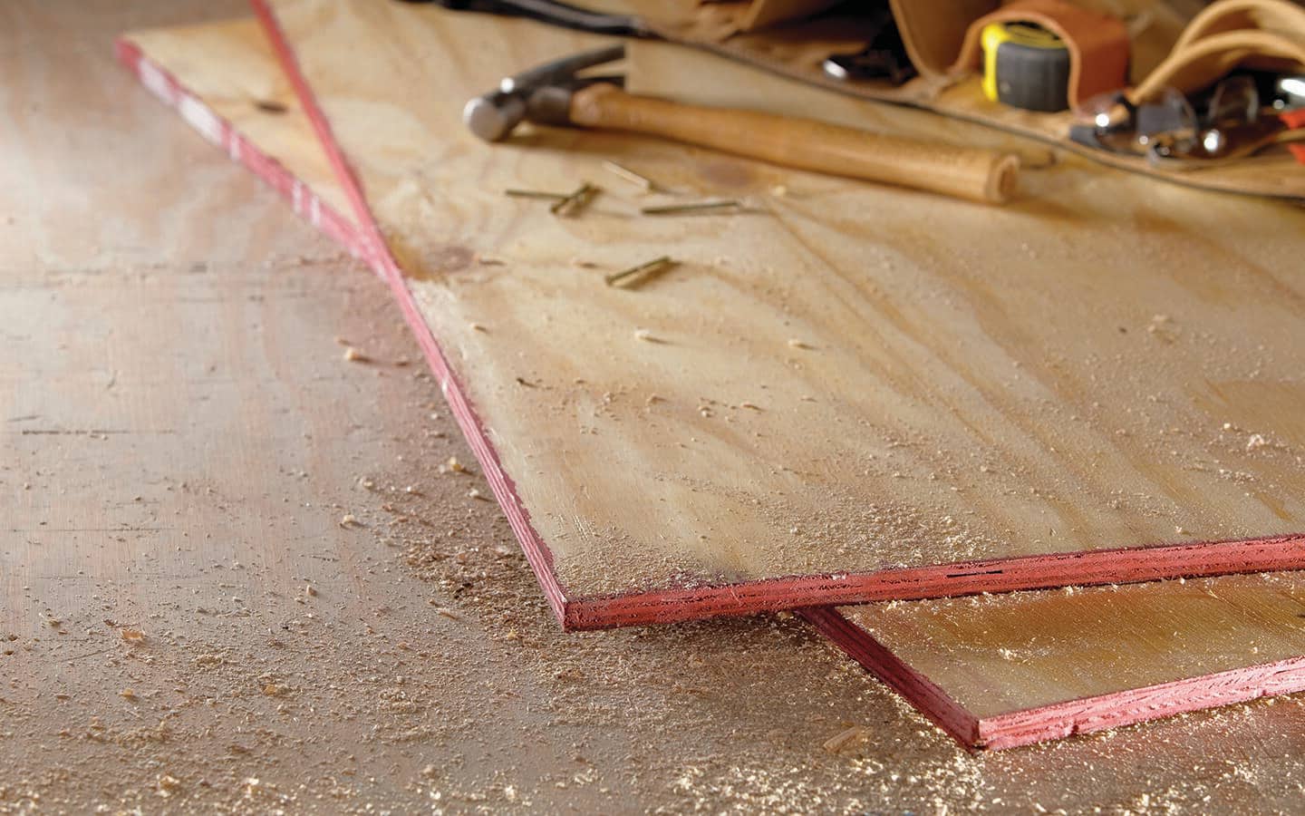 Two sheets of plywood lying on a concrete floor.