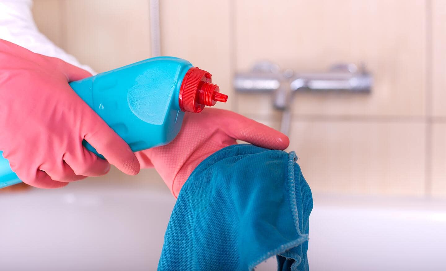 A person pours cleaner onto a rag.