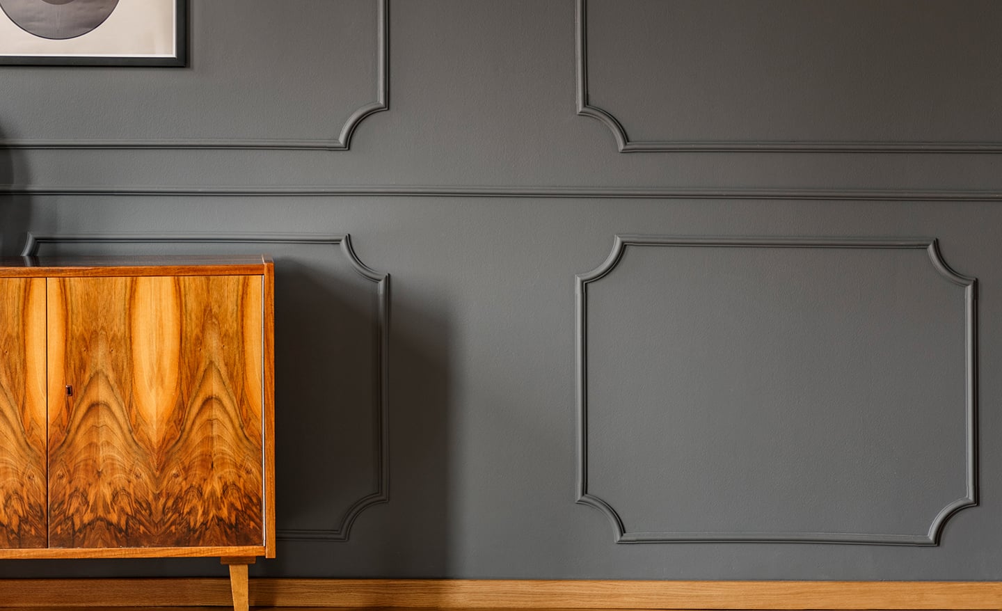 An intricate wall moulding design installed behind a wood buffet.