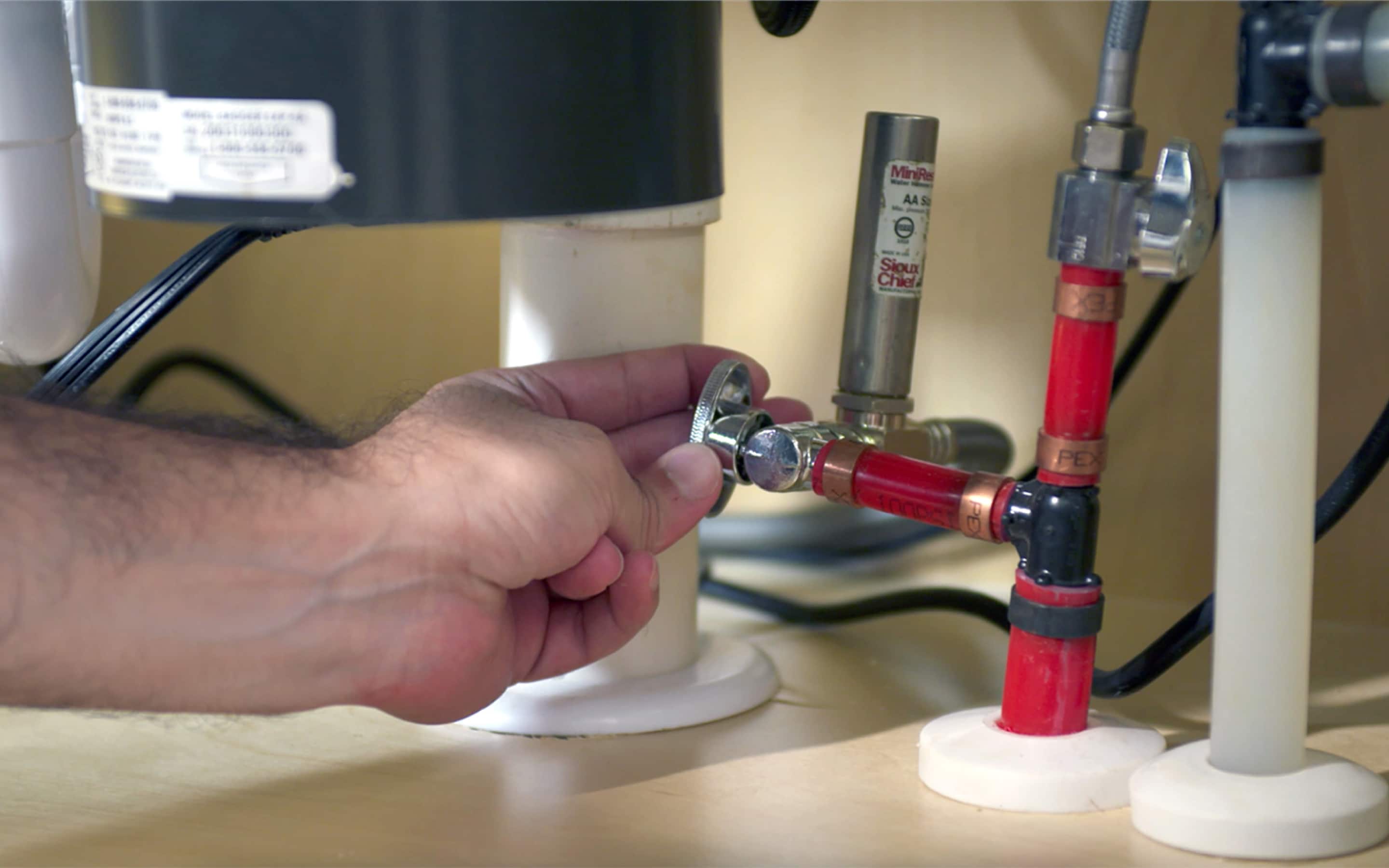 A Pro turns on the water supply for a dishwasher. A Pro turns on the water supply for a dishwasher.