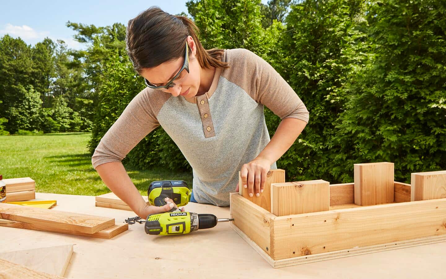 A person uses a drill to attach one side of the root cellar box. A person uses a drill to attach one side of the root cellar box.