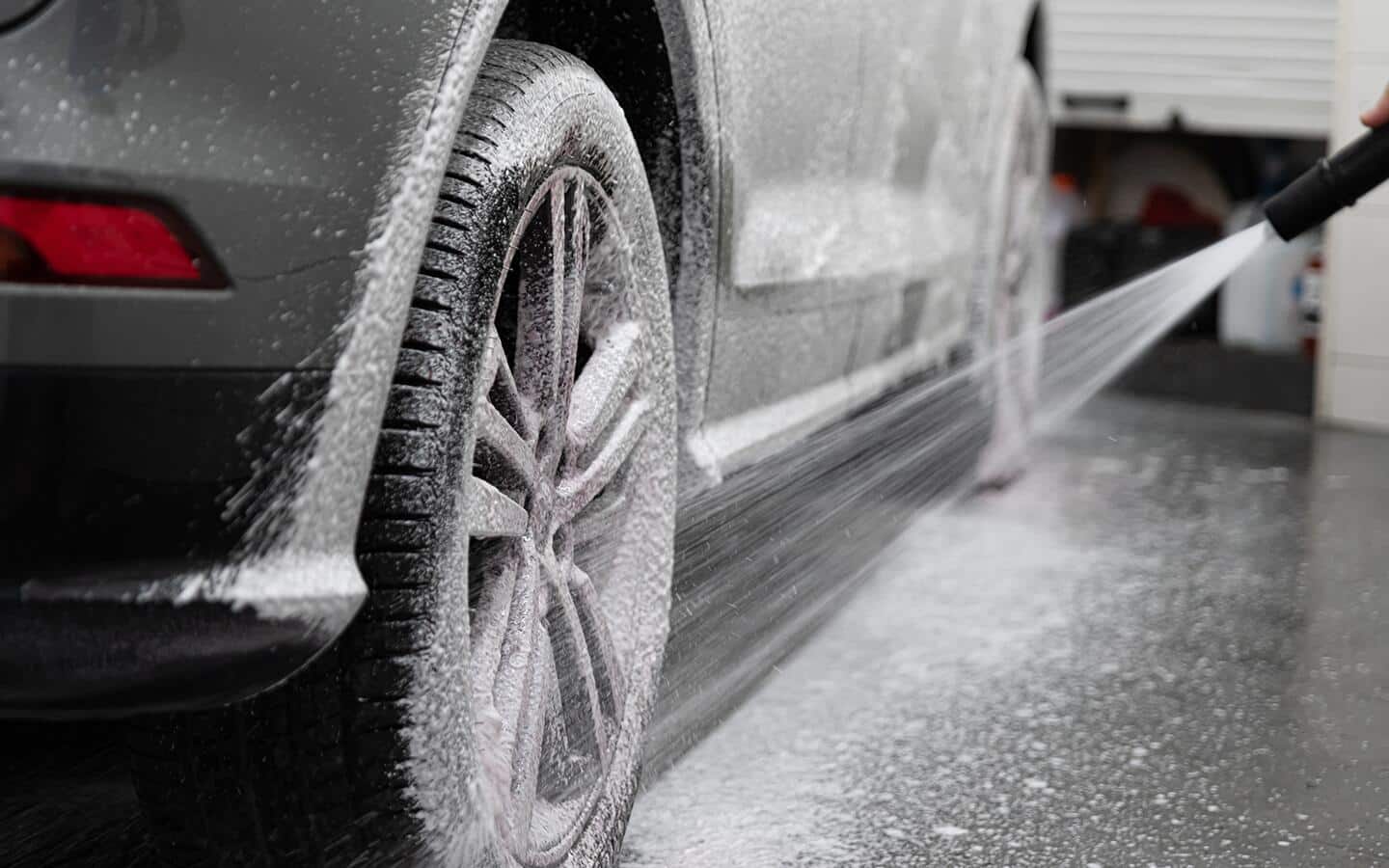 A person rinses off a tire with spray from a hose.