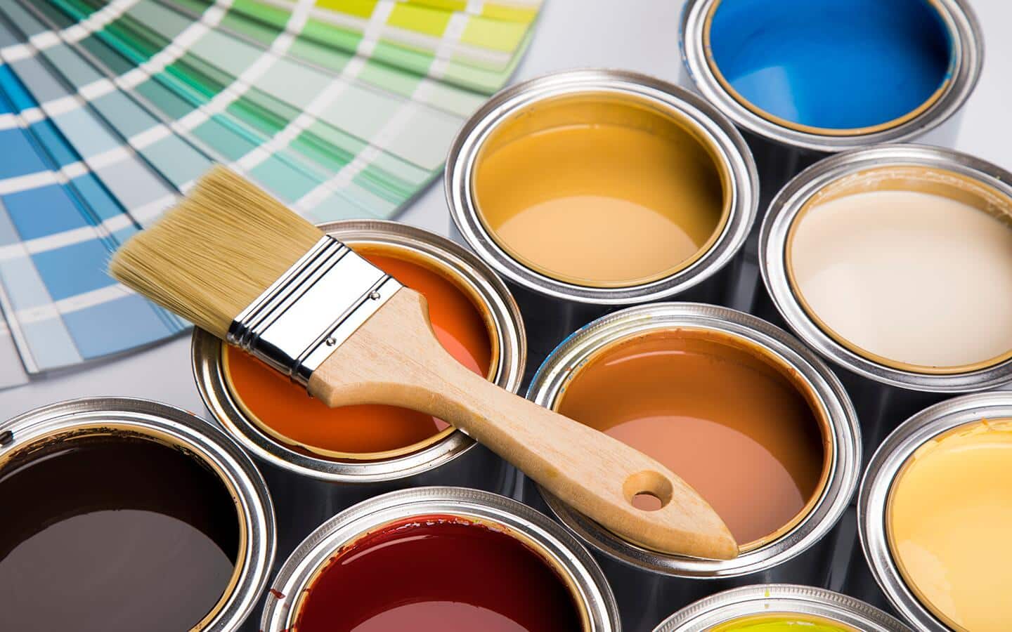 Different paint cans filled with paint with a paint brush resting atop. Different paint cans filled with paint with a paint brush resting atop.