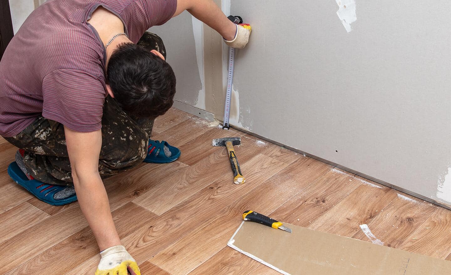 A person is measuring a drywall with a tape measure.