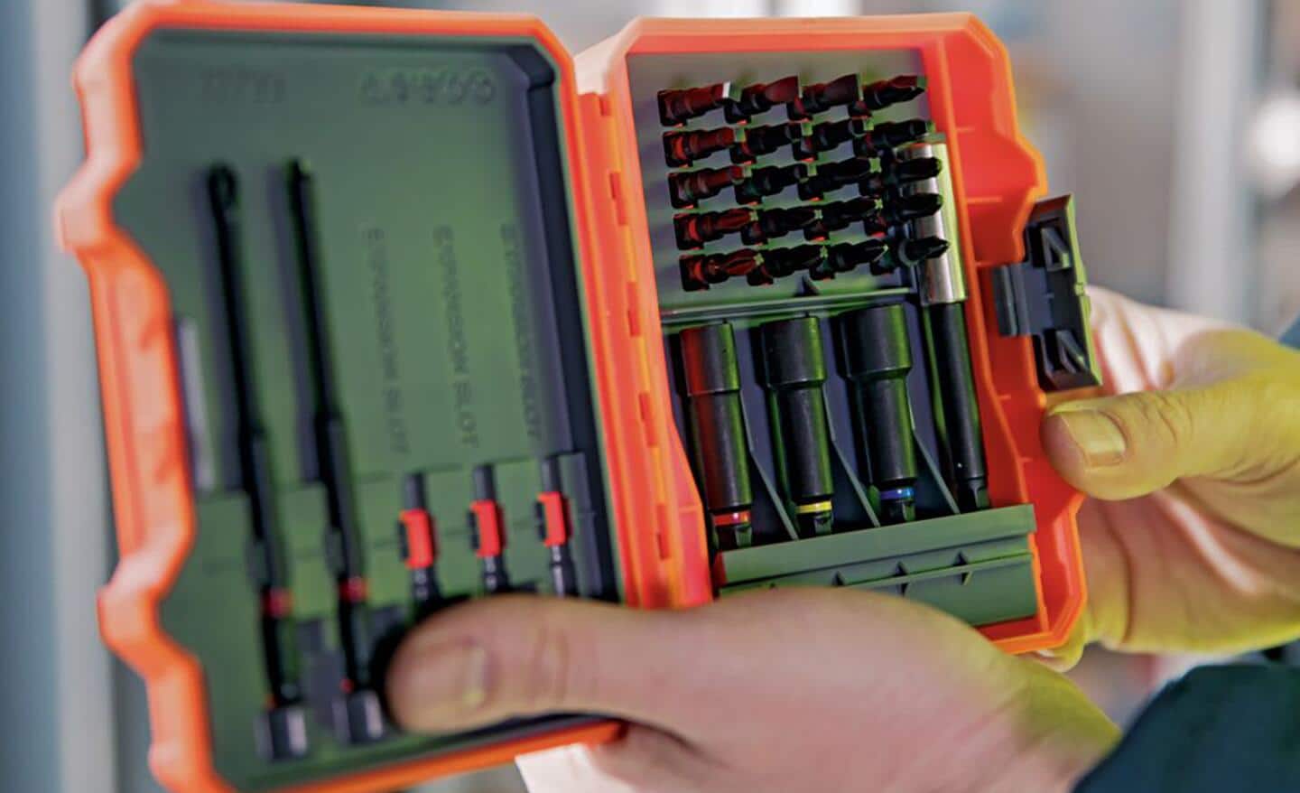 A person holds a drill bit kit with different types of drill bits.
