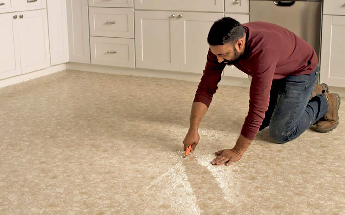 Vinyl flooring in a kitchen being cut with a utility knife. Vinyl flooring in a kitchen being cut with a utility knife.