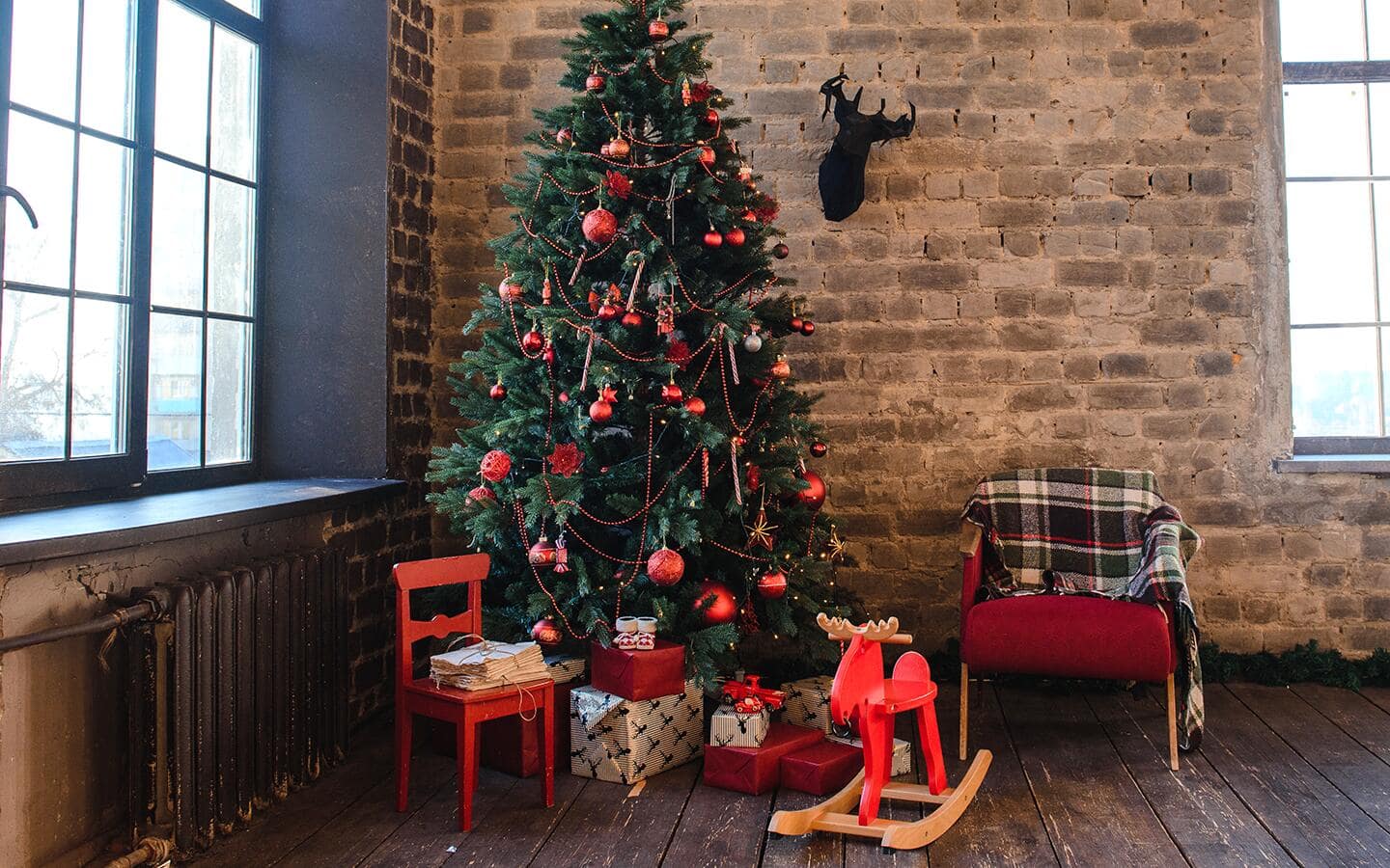 A decorated Christmas tree and various gifts next to a furnace and window. A decorated Christmas tree and various gifts next to a furnace and window.