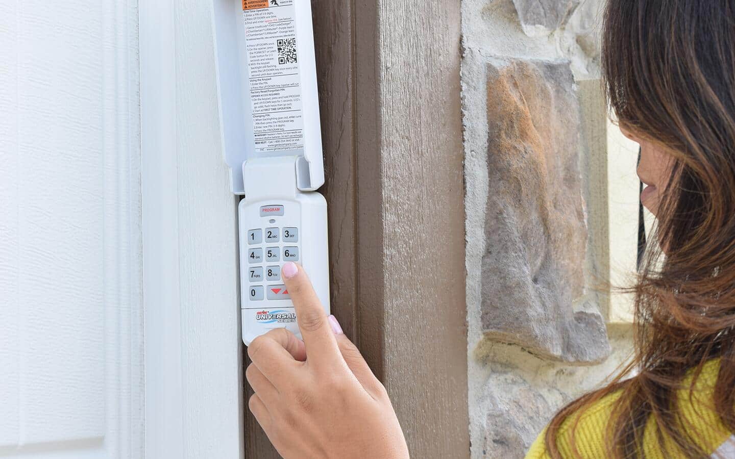 A person uses wall mounted controller to open a garage door.