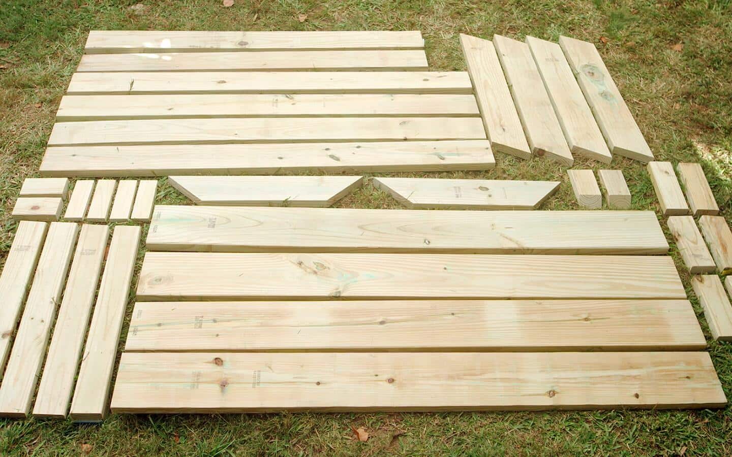 Wooden parts of a picnic table arranged on grass. Wooden parts of a picnic table arranged on grass.