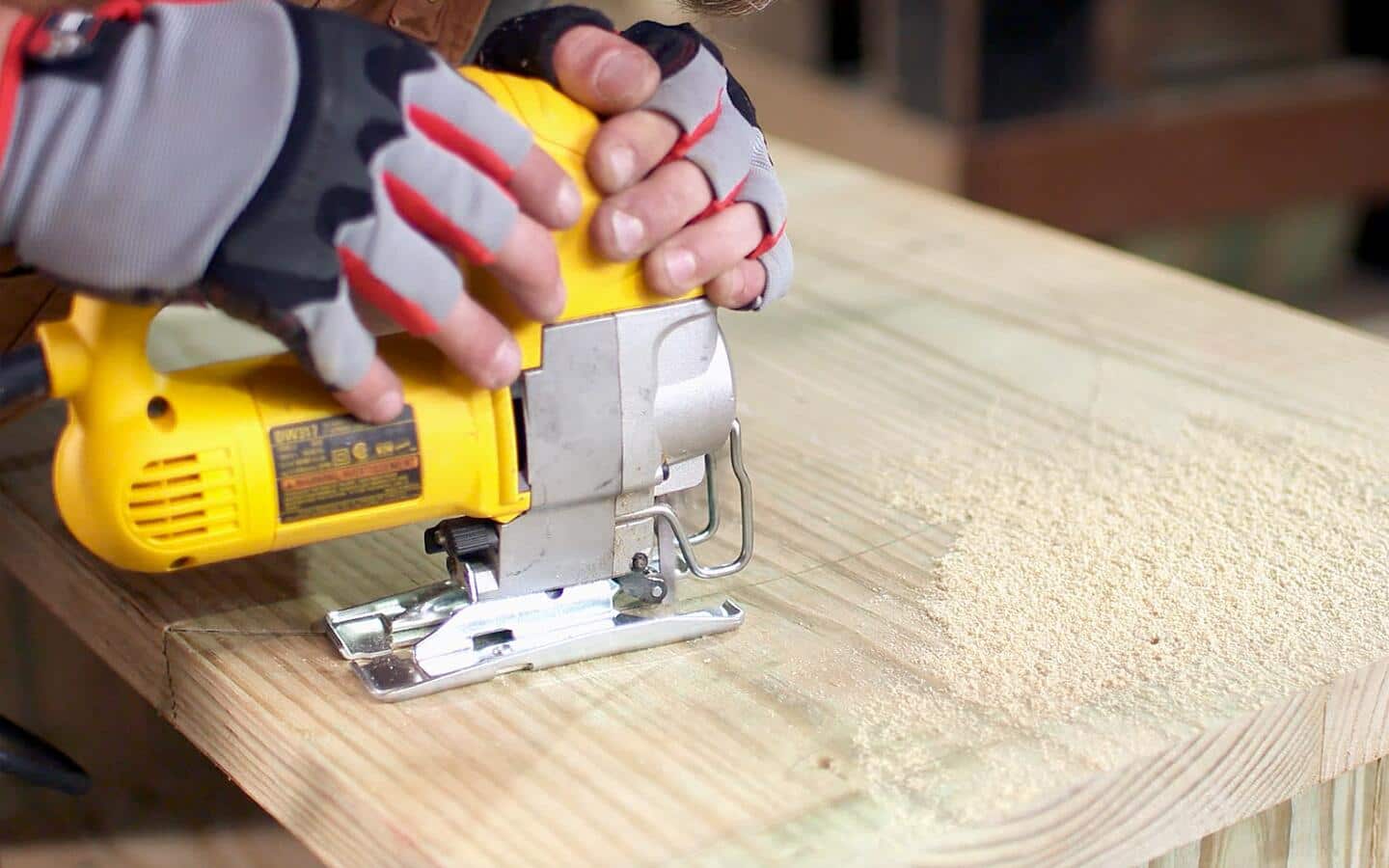 Someone uses a yellow jigsaw to cut out the circle for a grill hole.
