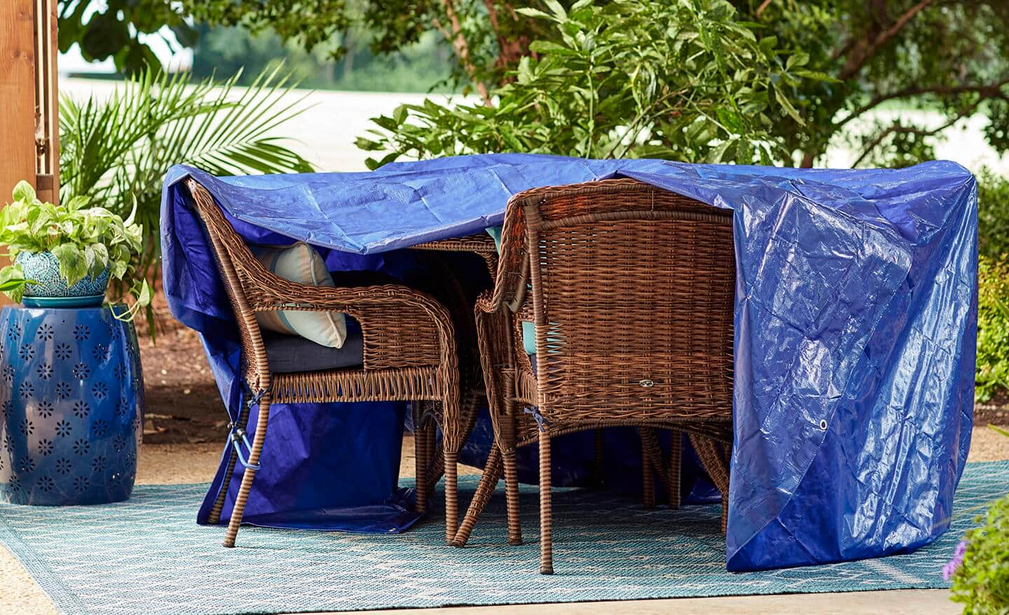 A blue tarp partially covering outdoor patio furniture.