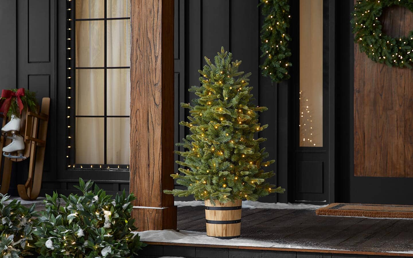 An artificial potted Christmas tree in the entryway of a home's front porch.