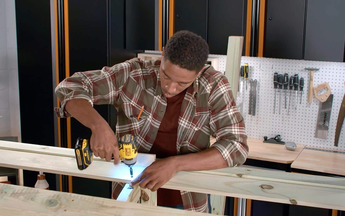 A person drills seat slats to an outdoor sofa being built in a workshop. A person drills seat slats to an outdoor sofa being built in a workshop.