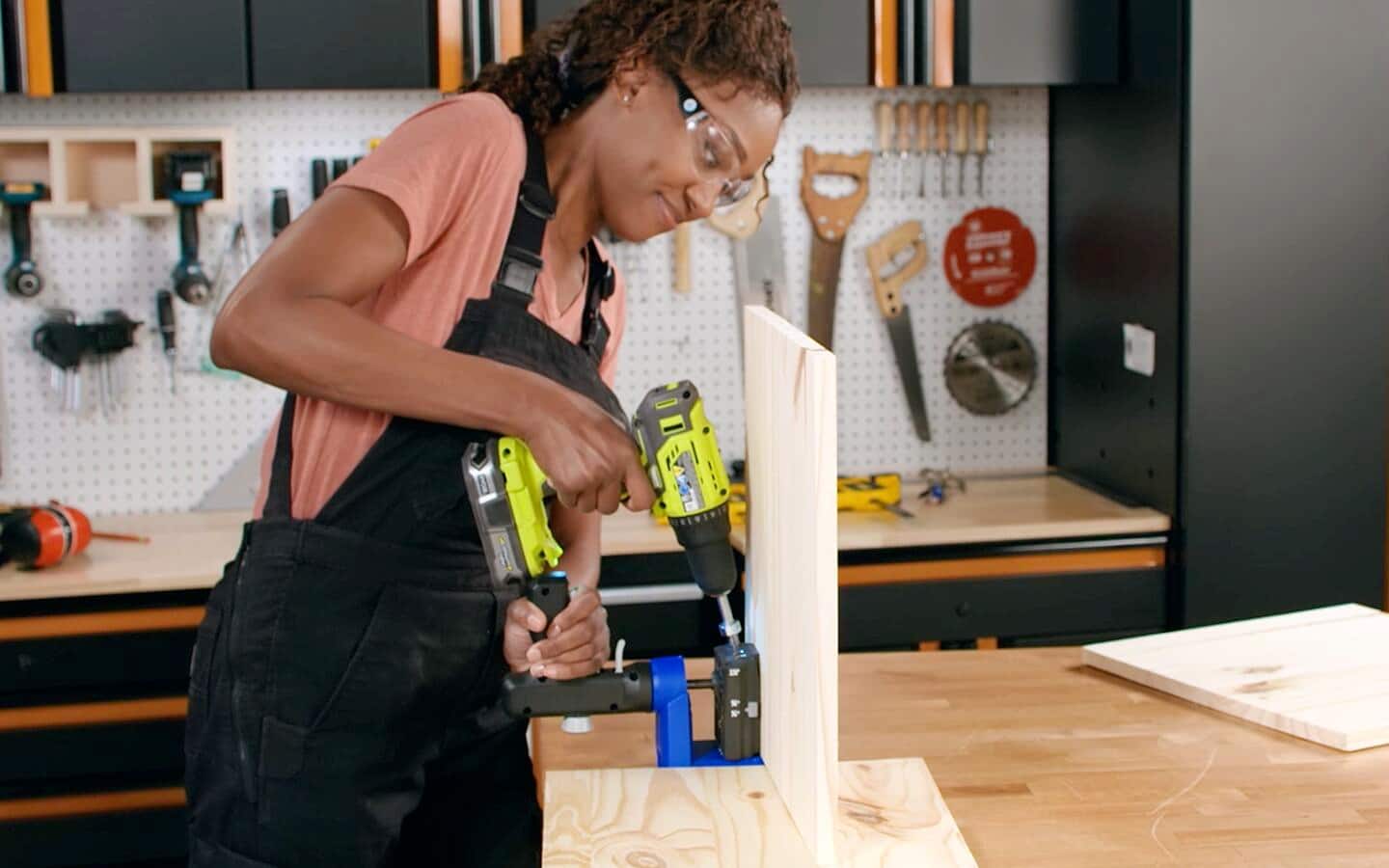 Someone uses a cordless drill and a pocket hole jig to make pocket holes in a board. Someone uses a cordless drill and a pocket hole jig to make pocket holes in a board.