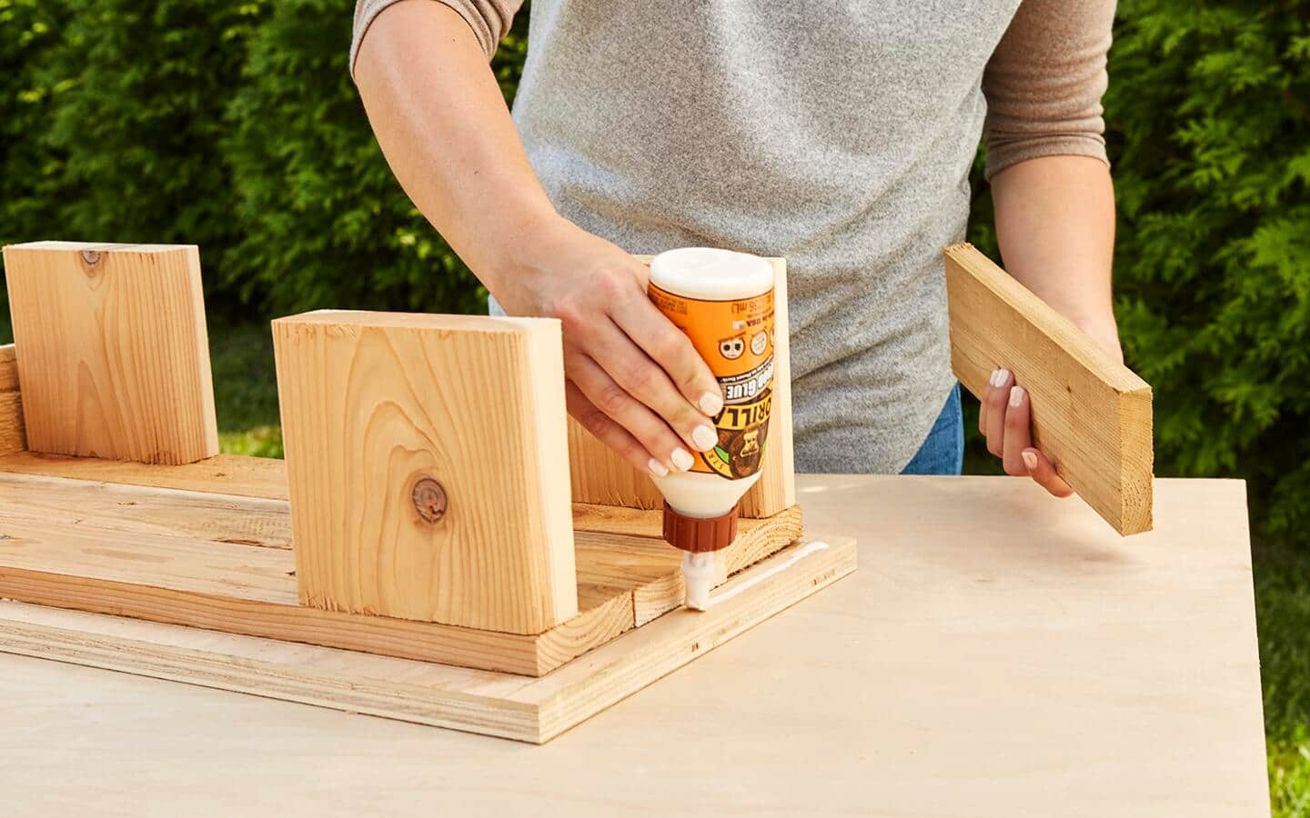 A person applies glue to a board before attaching the slats. A person applies glue to a board before attaching the slats.