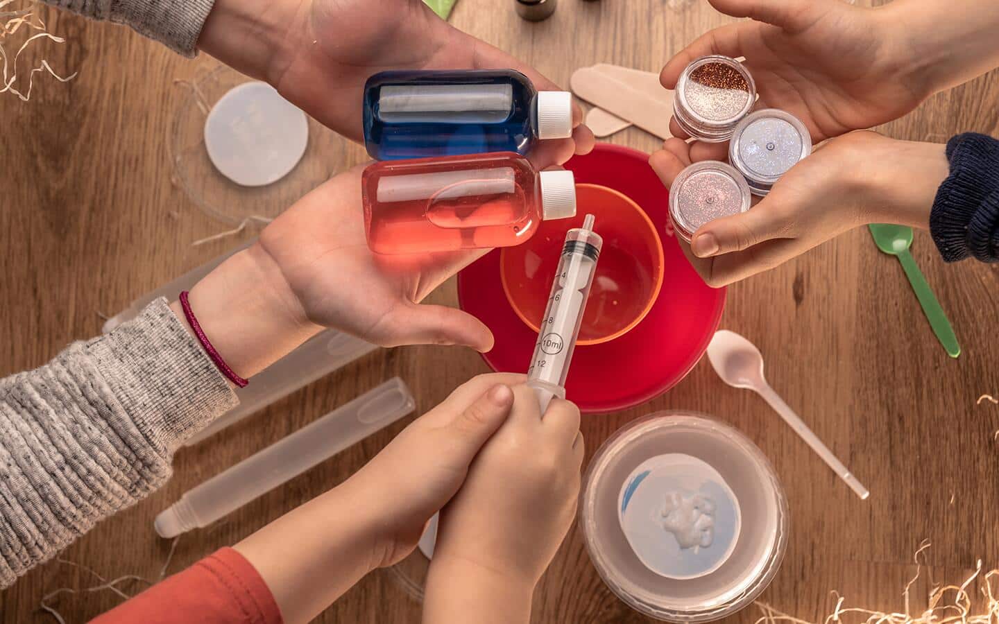 Hands showing different materials and tools for making slime. Hands showing different materials and tools for making slime.