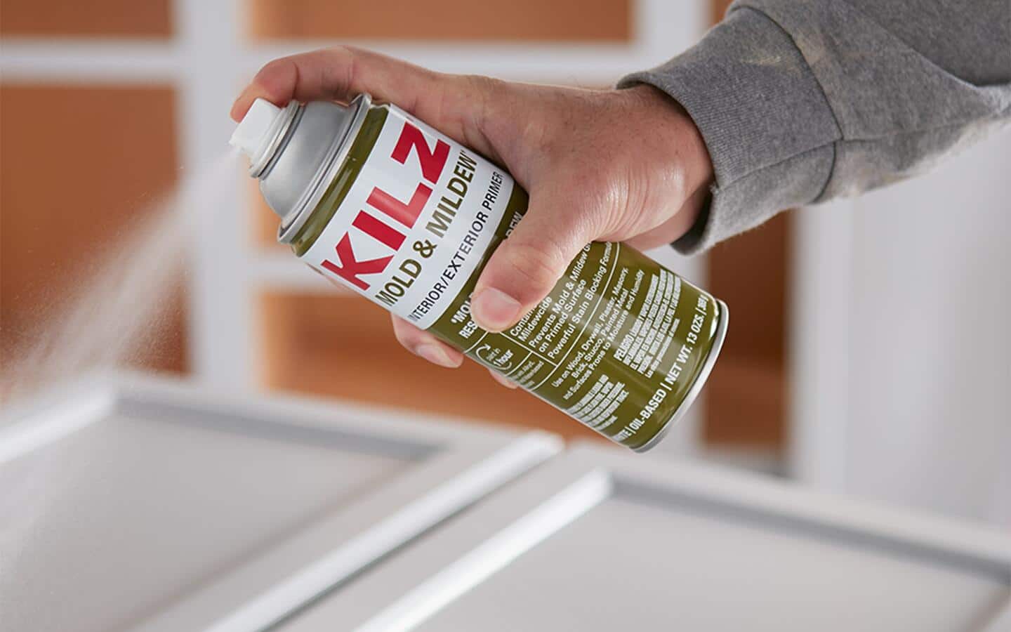 A person spraying primer onto a door. A person spraying primer onto a door.