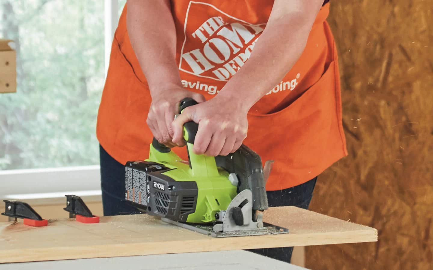 A Home Depot representative uses a circular saw to cut wood.
