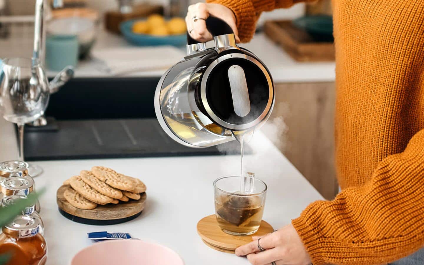 A person uses a kettle to pour hot water into a mug.