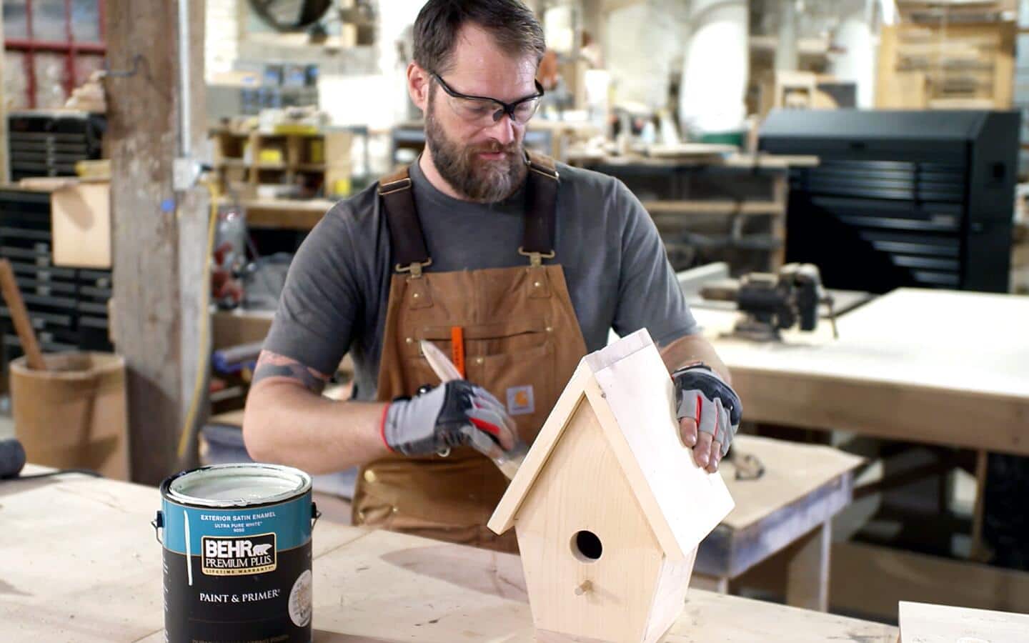 Someone paints the roof of a completed birdhouse.