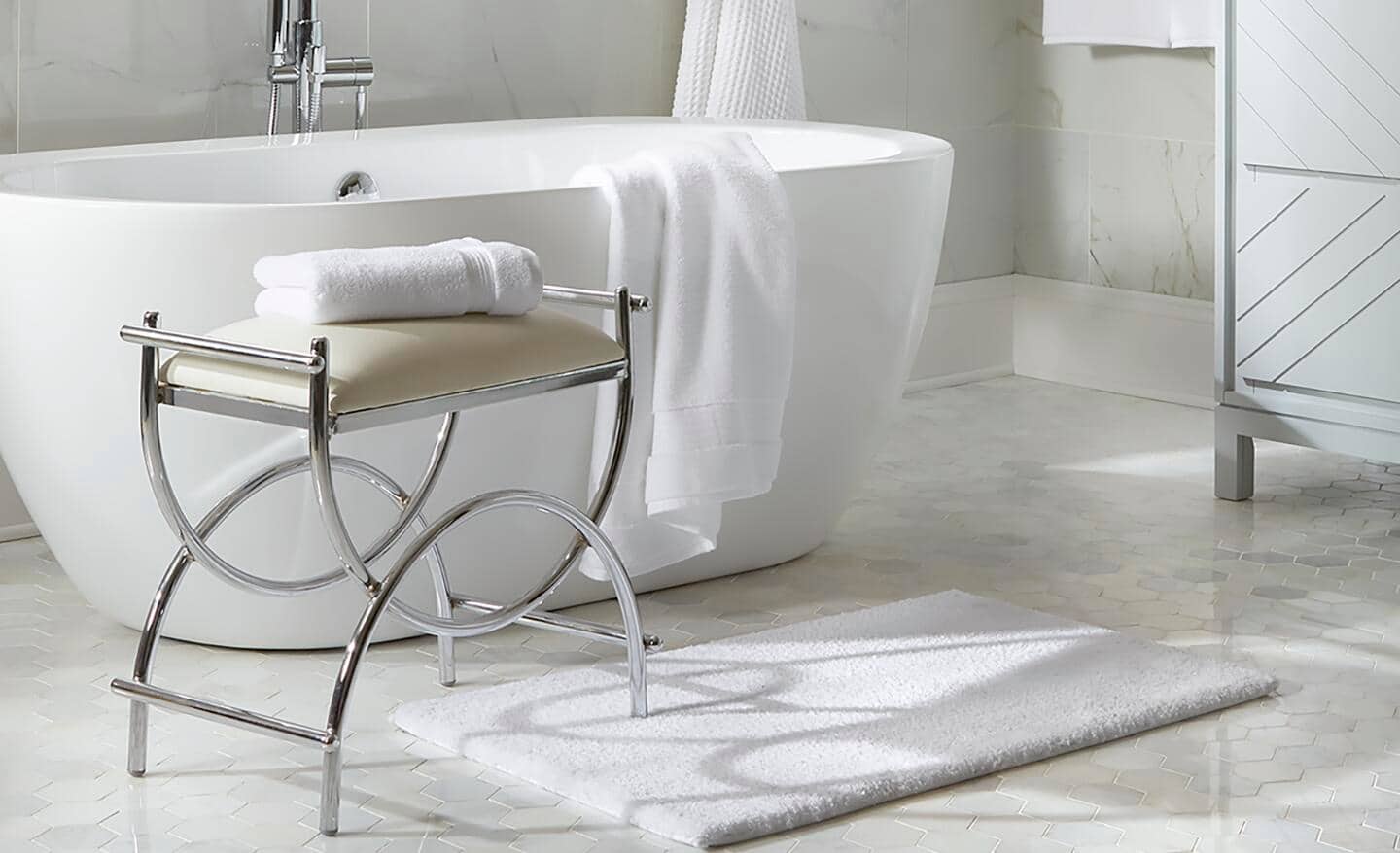 A fresh, white bath mat placed near a white bathtub.