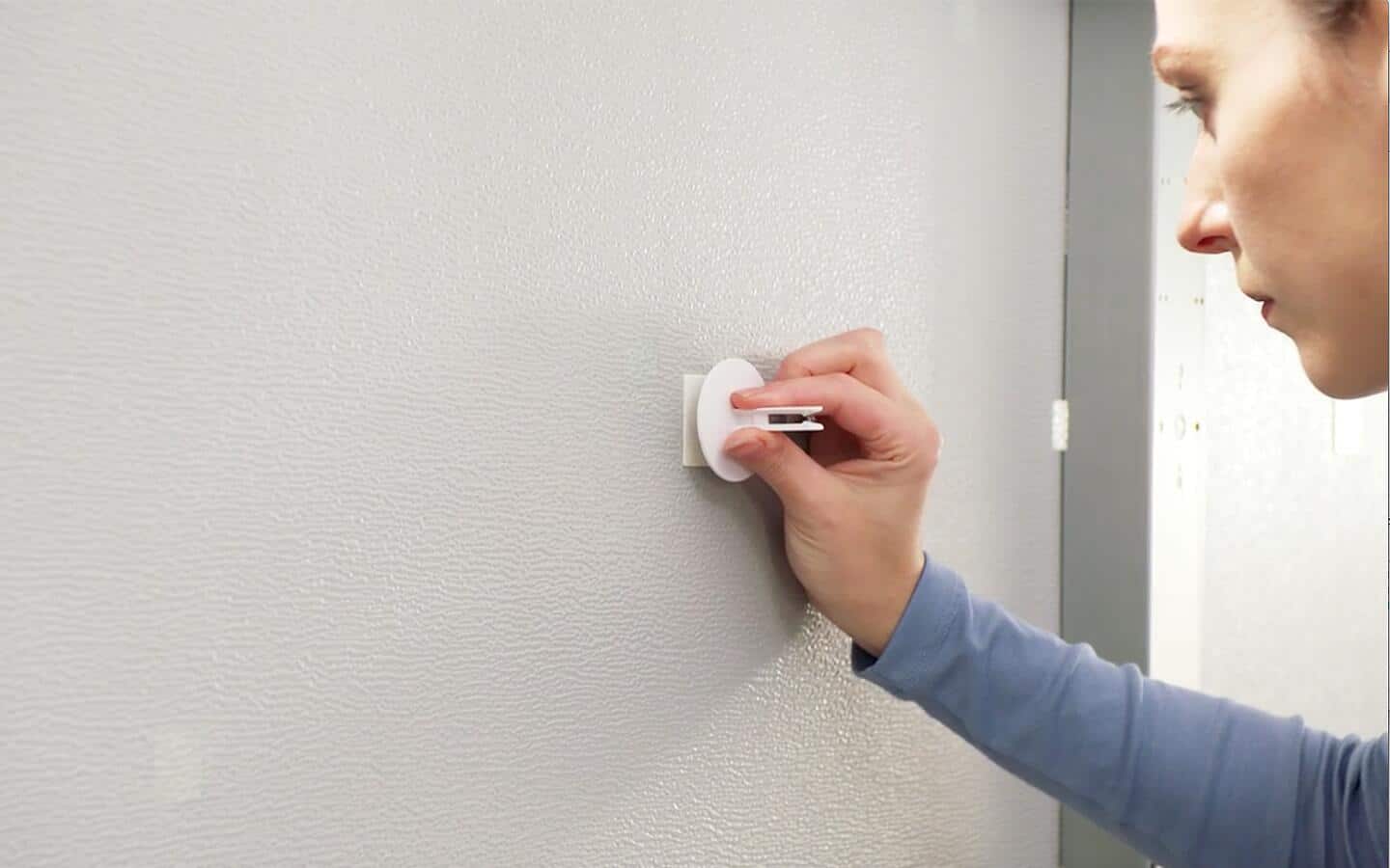 A person attaching a retainer clip to a piece of double-sided tape on a garage door.