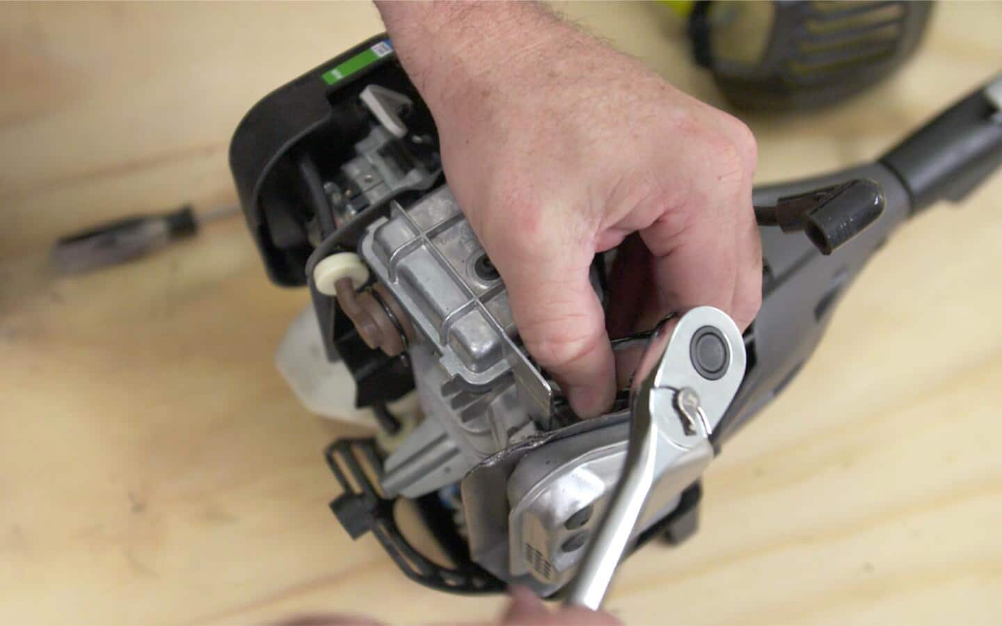 A person adjusting a spark plug on a string trimmer.