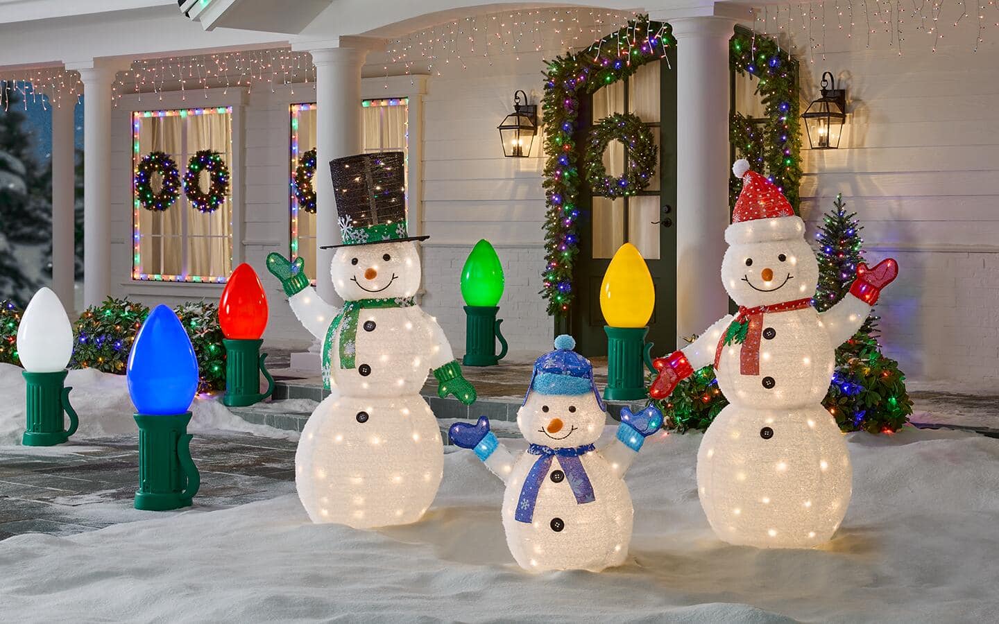 Lighted snowman and oversized Christmas bulb holiday ornaments in a front yard. Lighted snowman and oversized Christmas bulb holiday ornaments in a front yard.