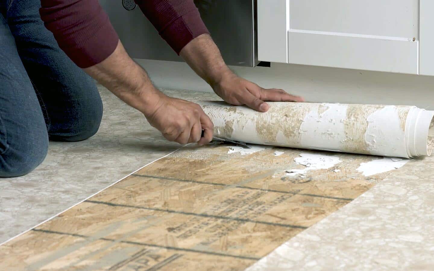 A person using a floor scraper tool to remove vinyl flooring's glued sections. A person using a floor scraper tool to remove vinyl flooring's glued sections.