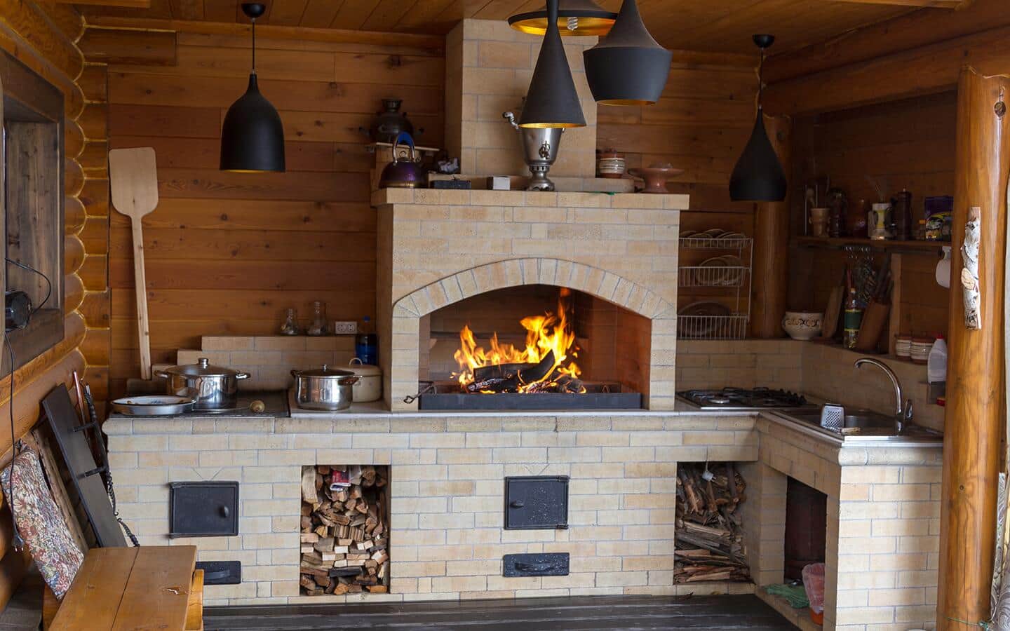 A brick fireplace with a wood fire and built-in kitchen amenities.
