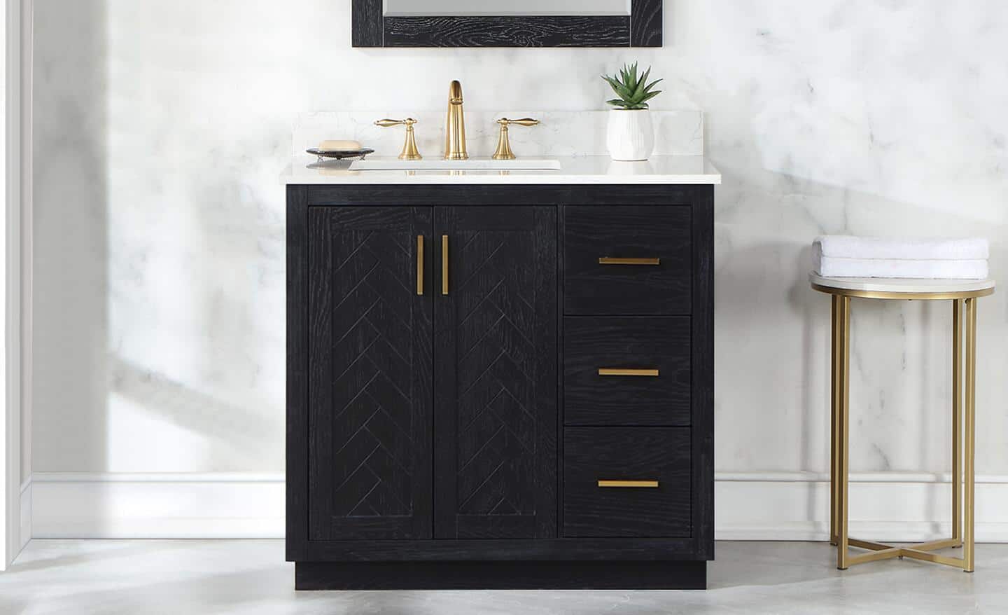 A black bath vanity with gold hardware installed in a small bathroom.