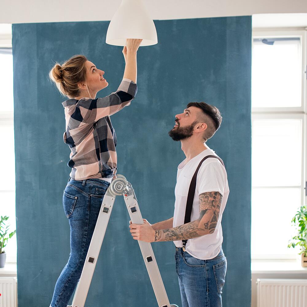 Two people change a light bulb in a ceiling fixture. Two people change a light bulb in a ceiling fixture.