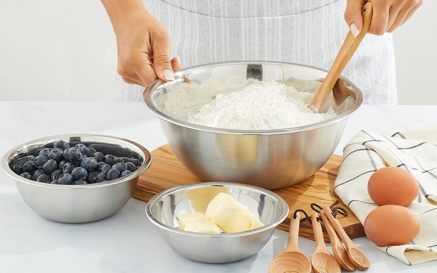 Someone making a recipe using stainless steel bowls.