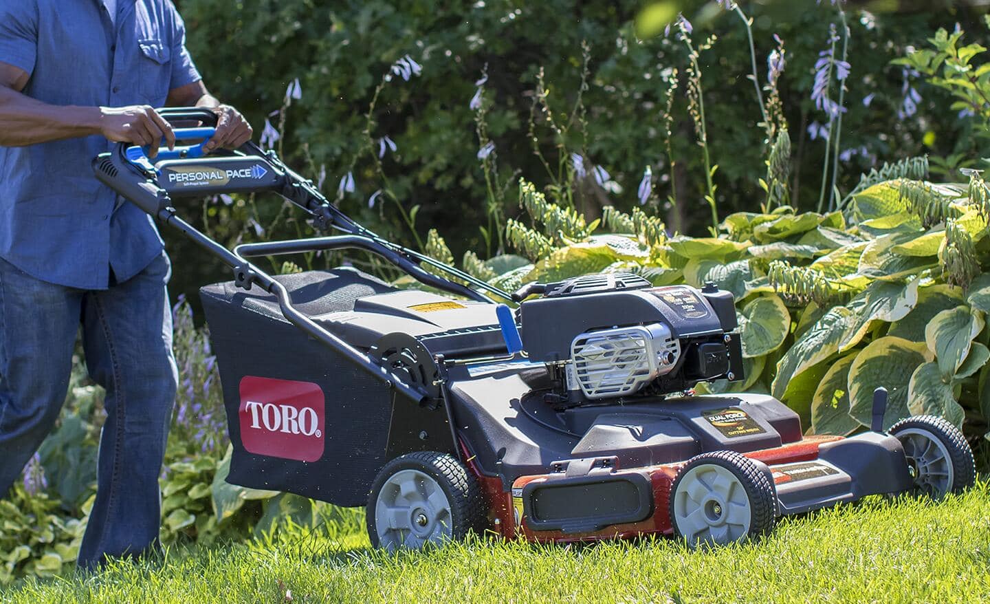 A person mows a yard with a lawnmower.
