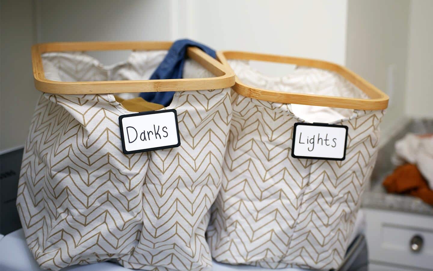 Two laundry bins sitting side-by-side on top of a counter. Two laundry bins sitting side-by-side on top of a counter.
