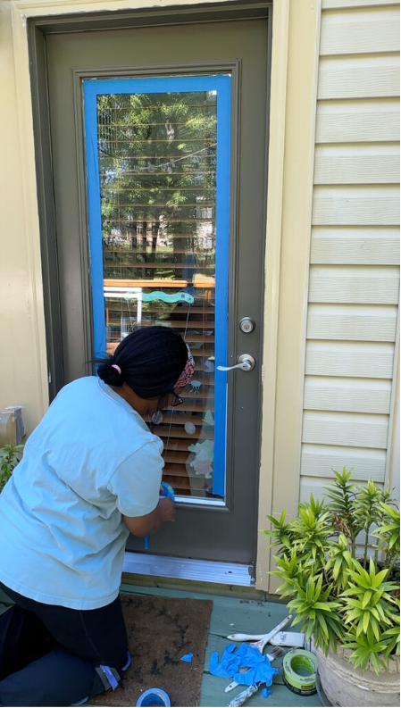 A person adding tape to the window of a door.