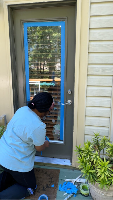 A person adding tape to the window of a door. A person adding tape to the window of a door.