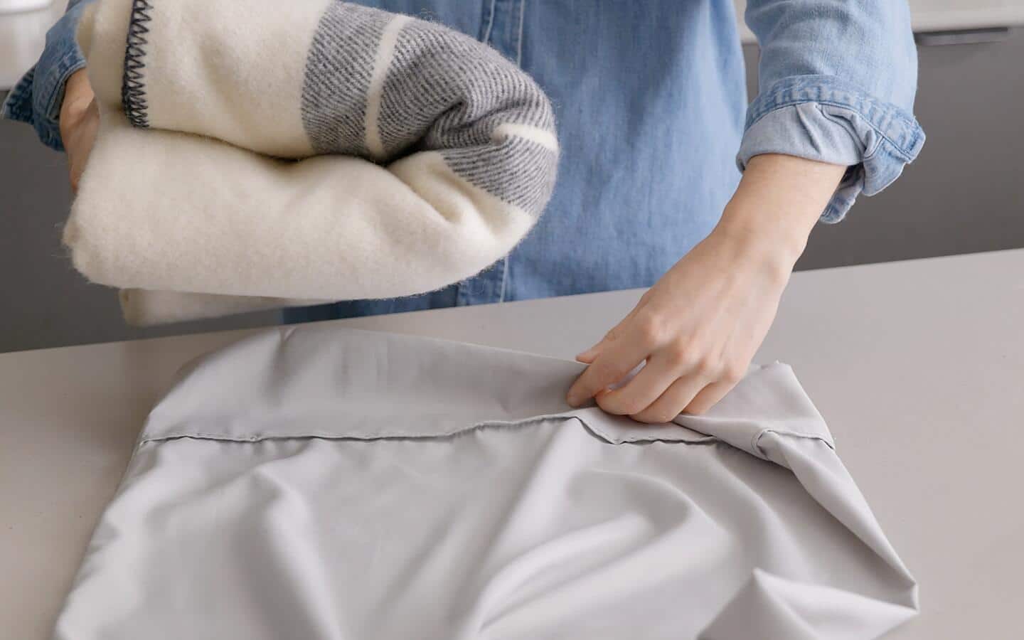 A white and blue-striped blanket is placed in a gray pillowcase.
