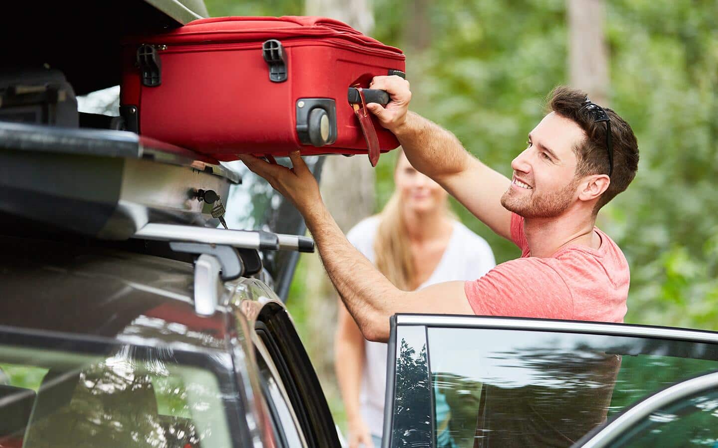 A person pulling a suitcase from the rack on top of a car. A person pulling a suitcase from the rack on top of a car.
