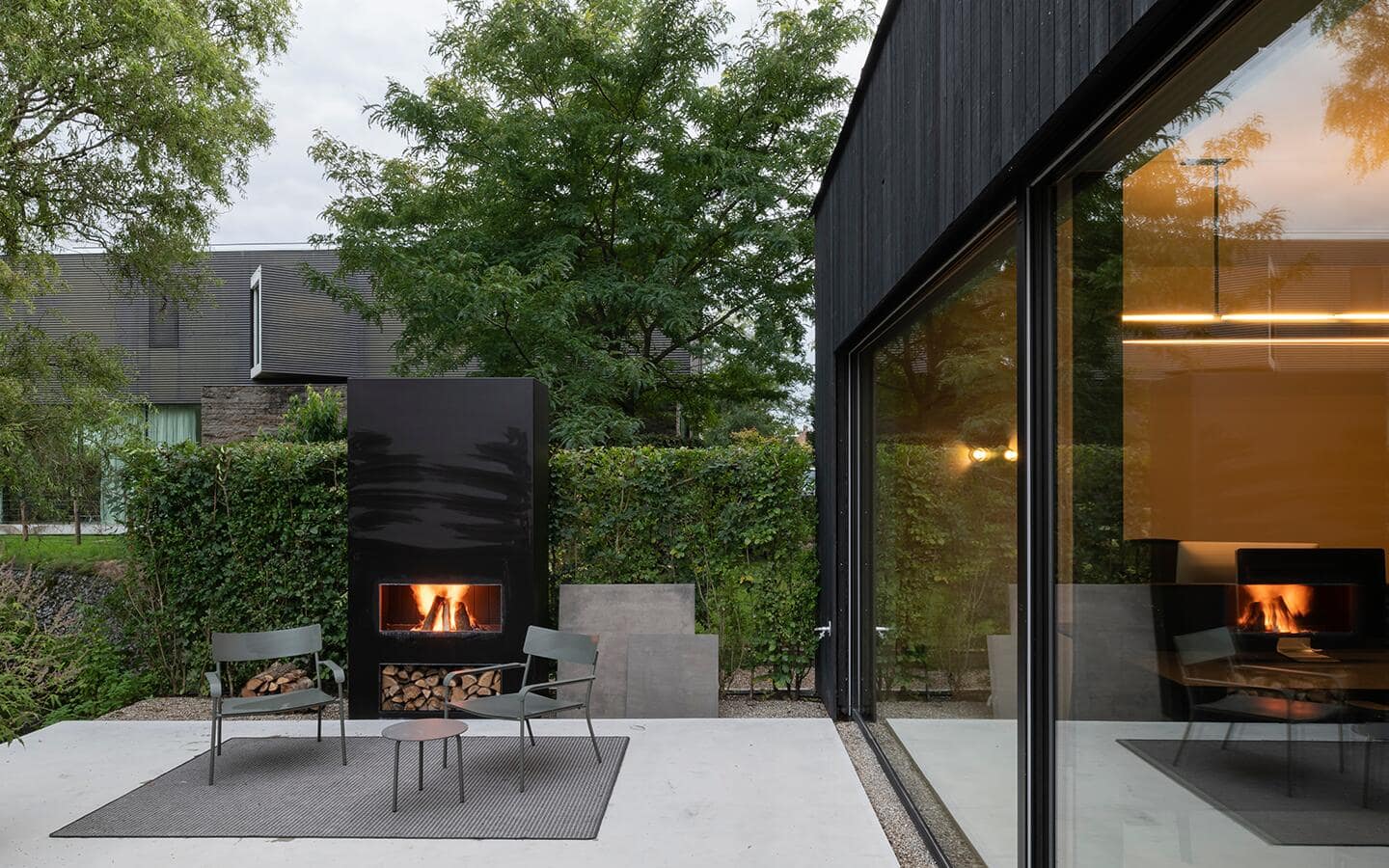 A black outdoor fireplace on a patio featuring modern seating.