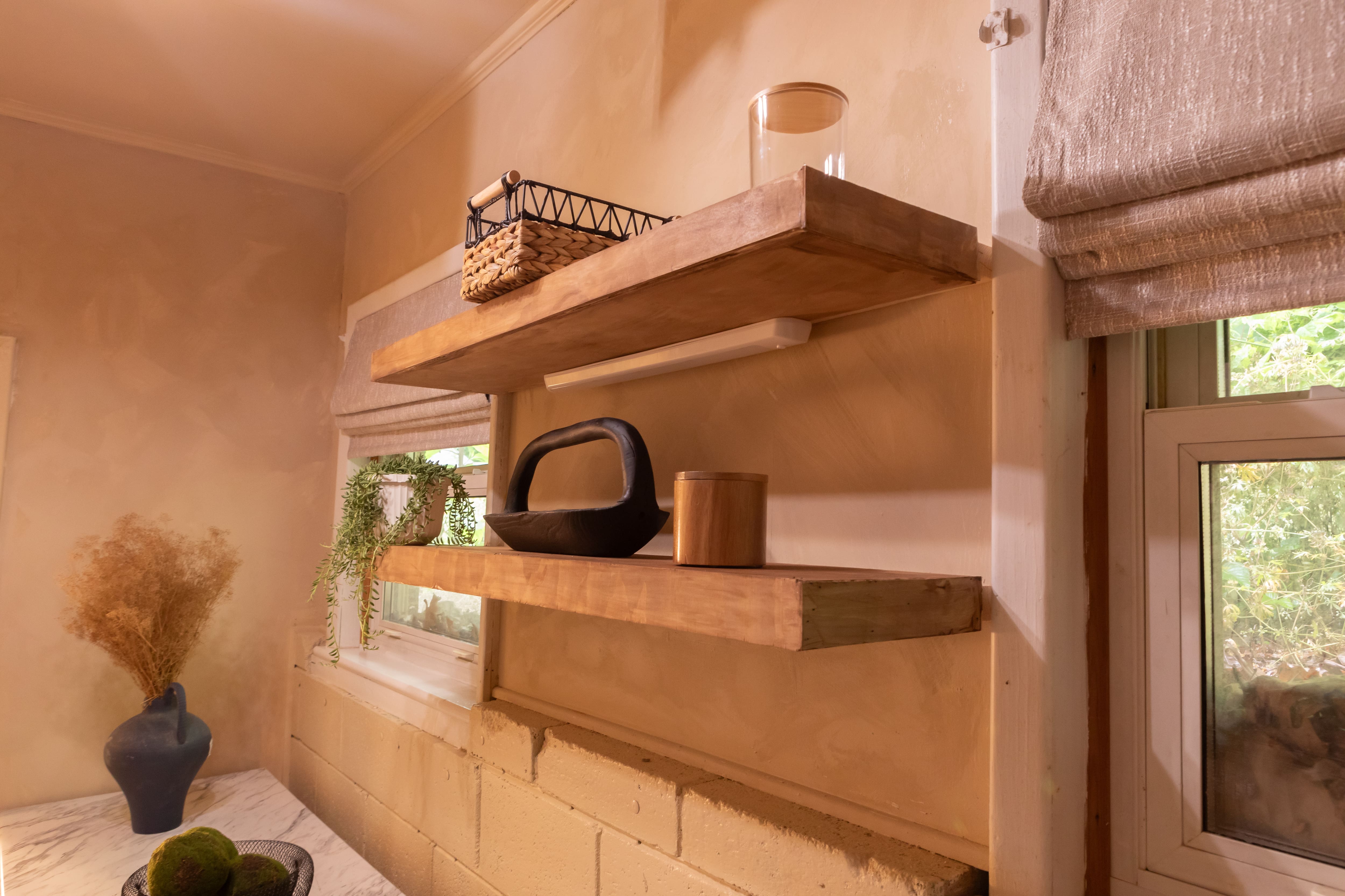 Wall mounted wood shelves with undermount LED lighting in a newly renovated laundry room.