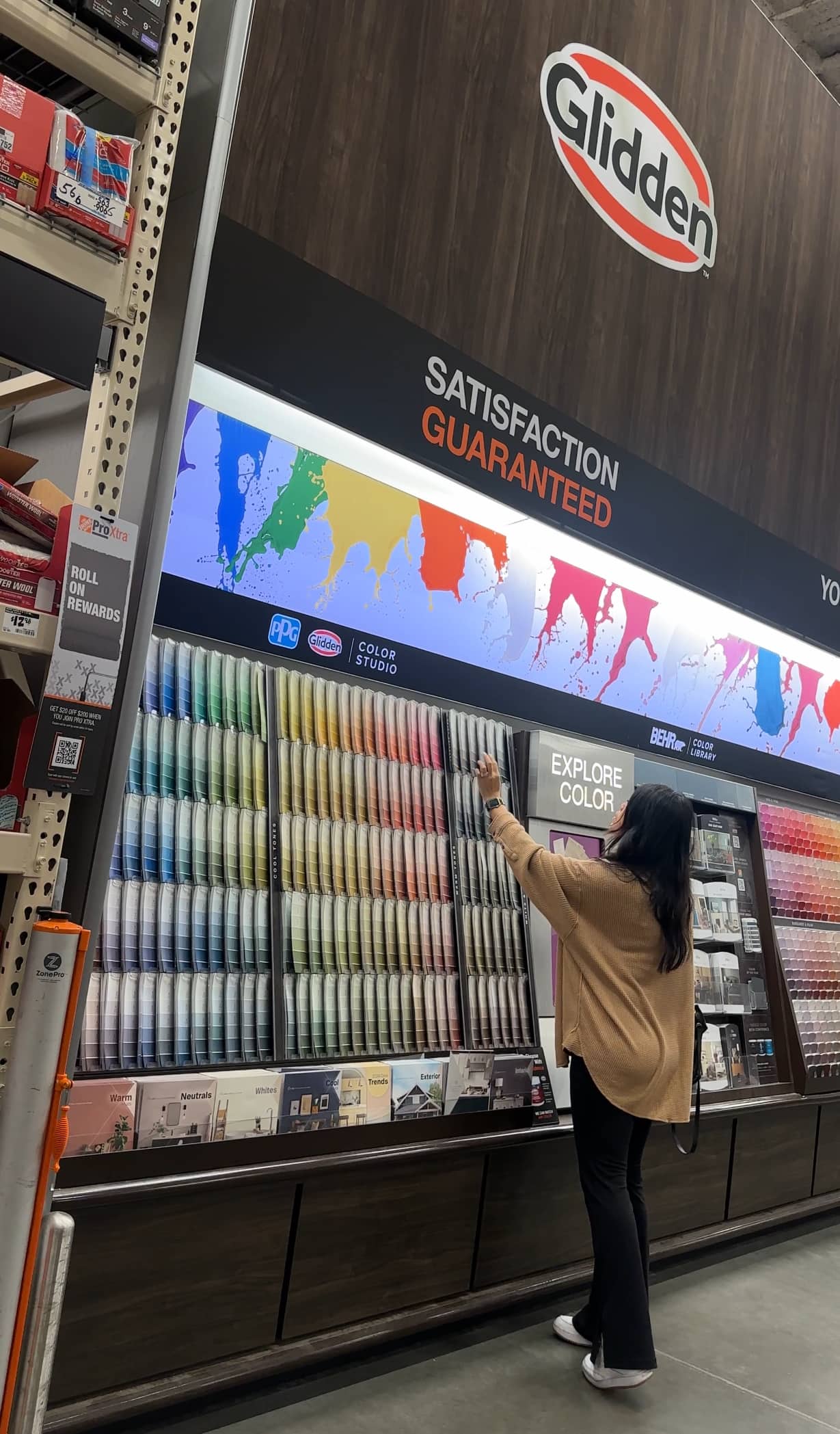 Sabrina standing in front of a wall of Glidden paint samples at The Home Depot, picking out the colors for her space’s interior