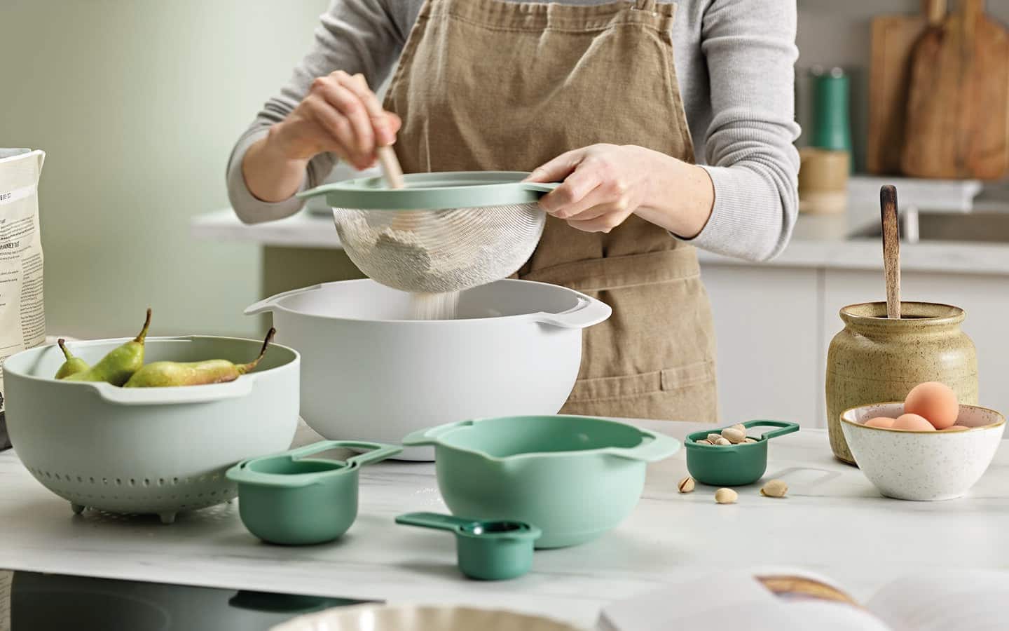 Someone using several different sized mixing bowls to make a cake.