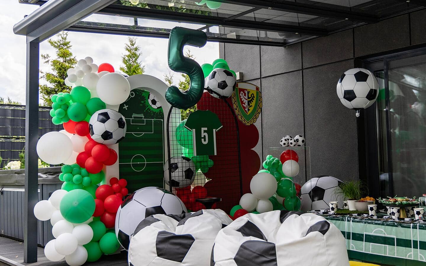 Soccer-themed balloons, beanbag chairs and other sports themed decor placed on a deck. Soccer-themed balloons, beanbag chairs and other sports themed decor placed on a deck.