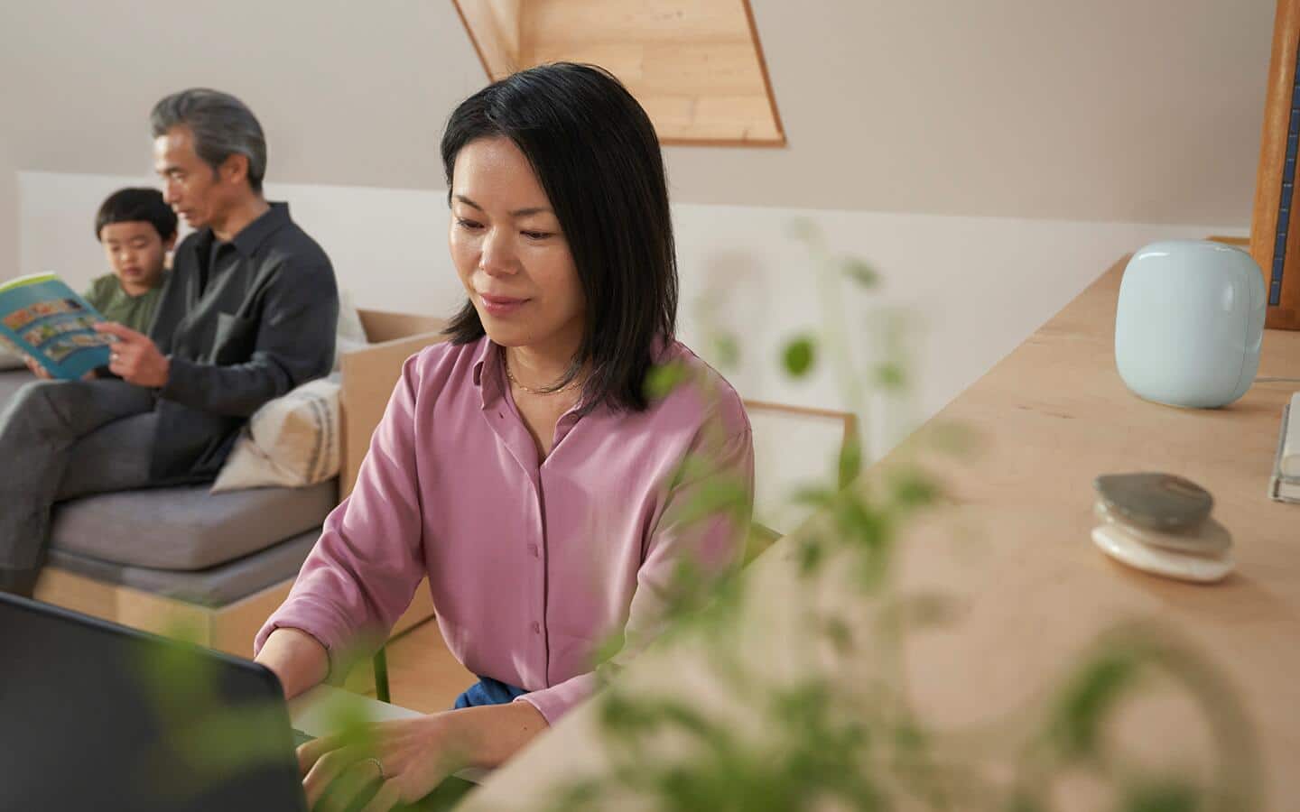 A woman uses a laptop computer with a smart speaker next to her. A woman uses a laptop computer with a smart speaker next to her.