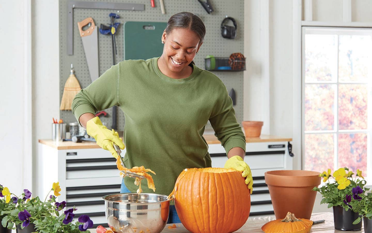 A person using a scoop to clean out a pumpkin and discard seeds in a bowl A person using a scoop to clean out a pumpkin and discard seeds in a bowl