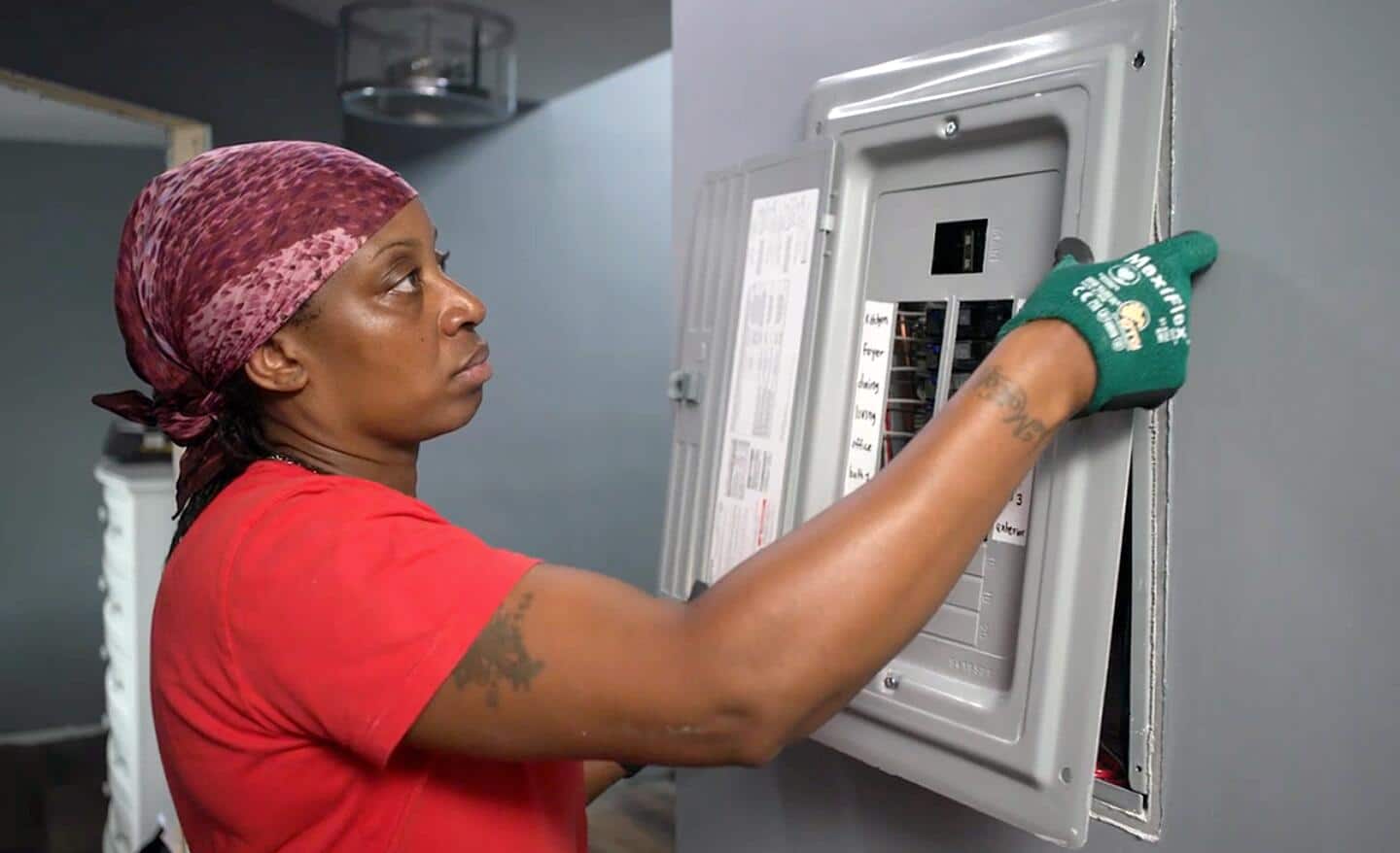 A person removing the panel cover of a circuit breaker.