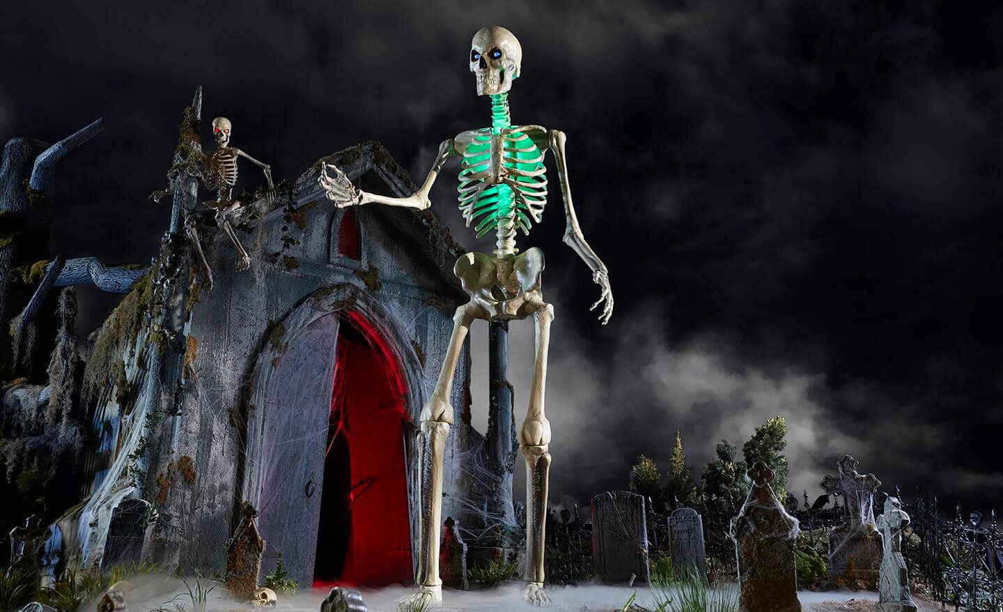 A 12-foot-tall skeleton glows in a dark yard decorated for Halloween.