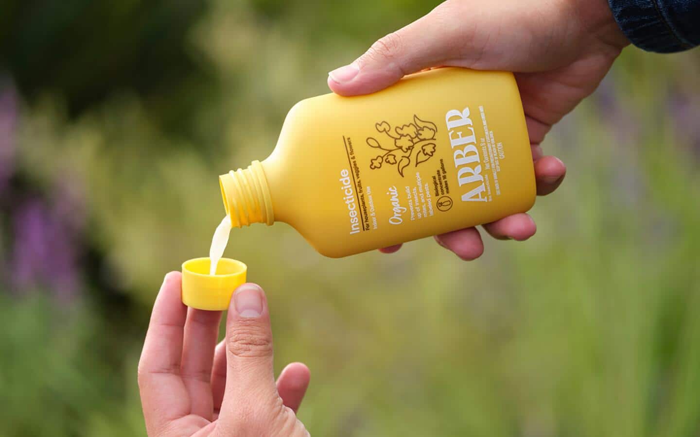 Someone pouring organic insecticide into the jar's cap. 